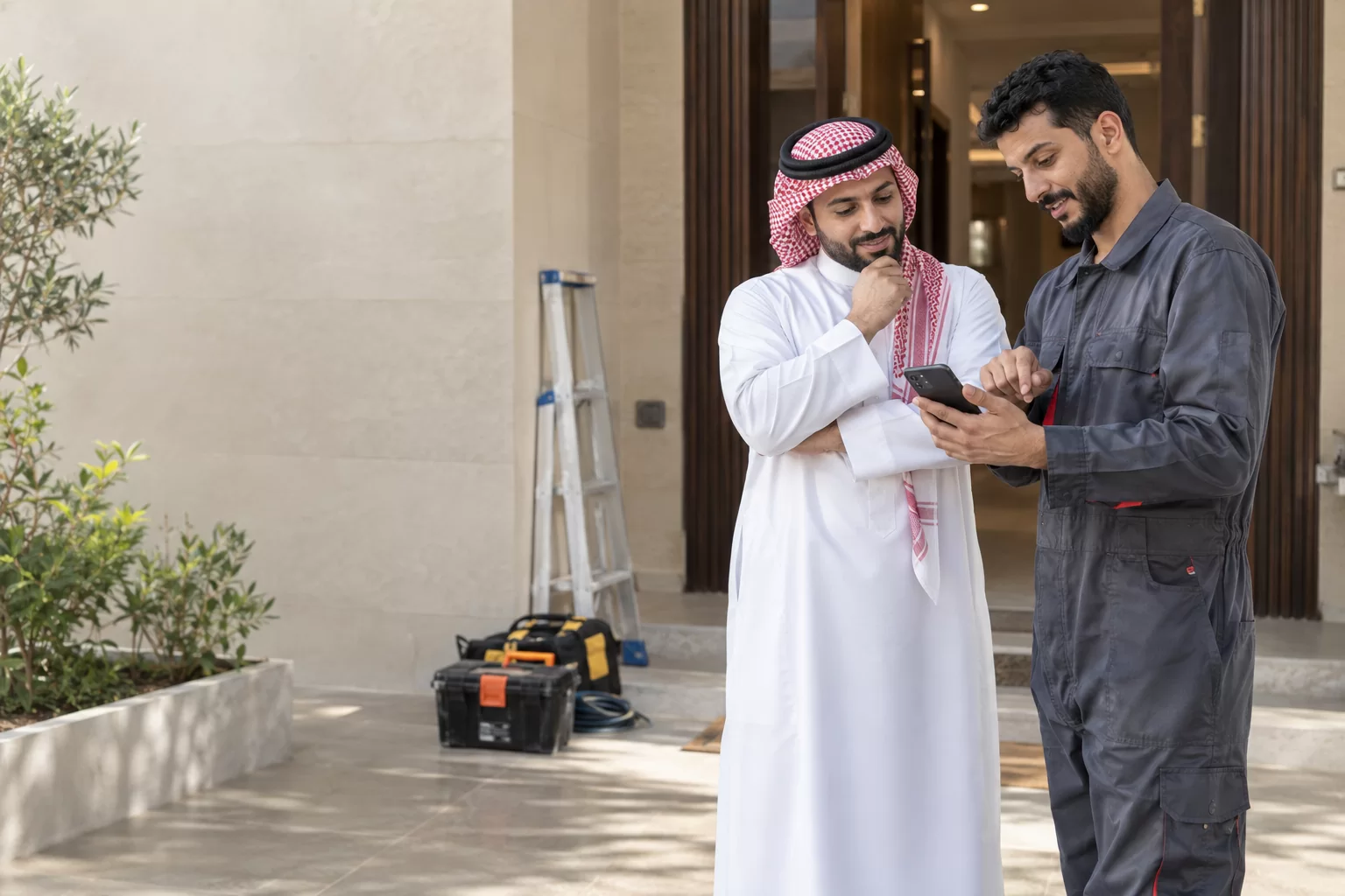عميل سعودي وفني خدمات يراجعان عرض السعر على الهاتف قبل بدء العمل